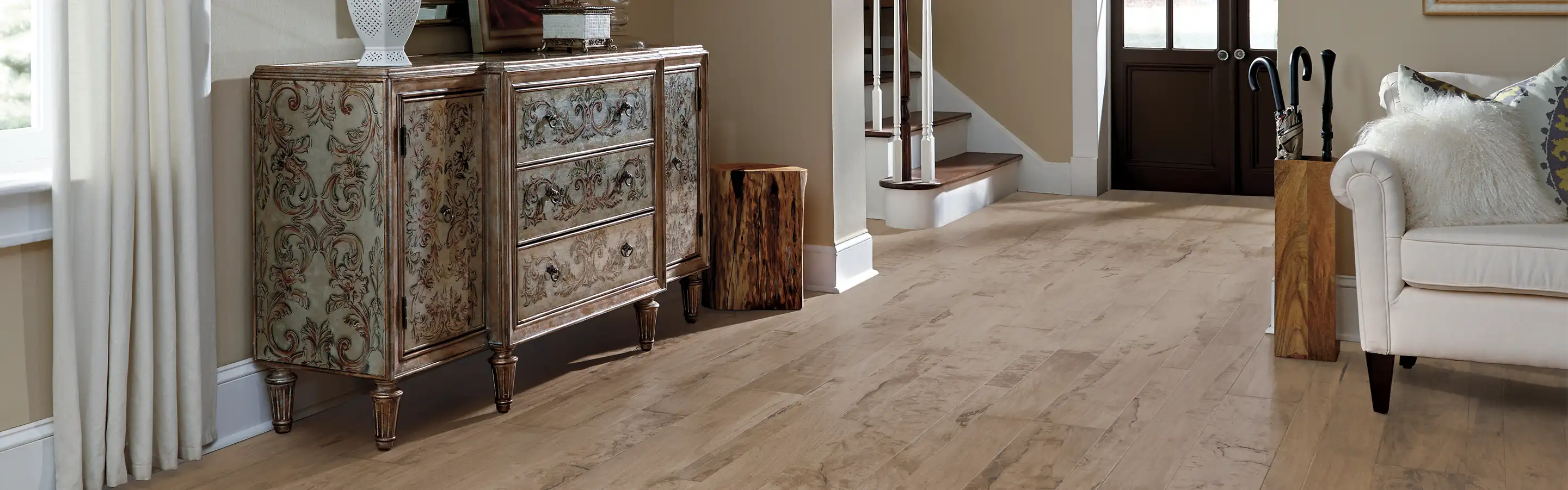 light hardwoods in entry way/living area with front brown wood doors and cream upholstered sofa